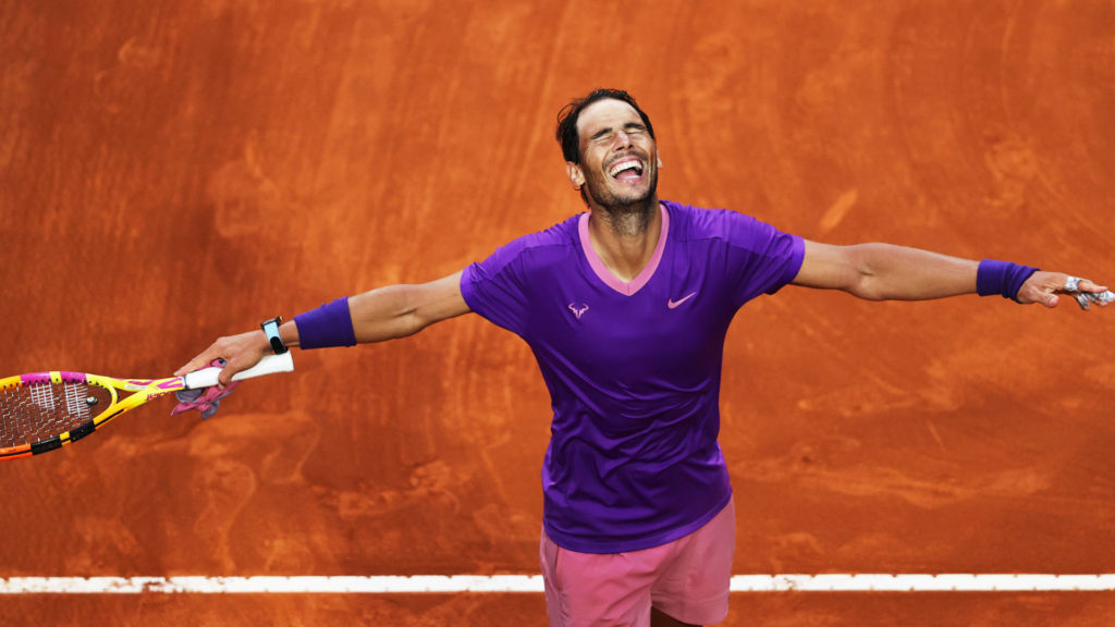 Rafael Nadal extends his arms out and lifts his face up with eyes closed and a smile