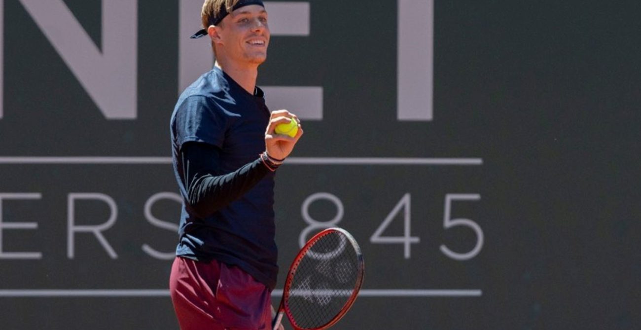 Denis Shapovalov smiles and holds up a ball in Geneva