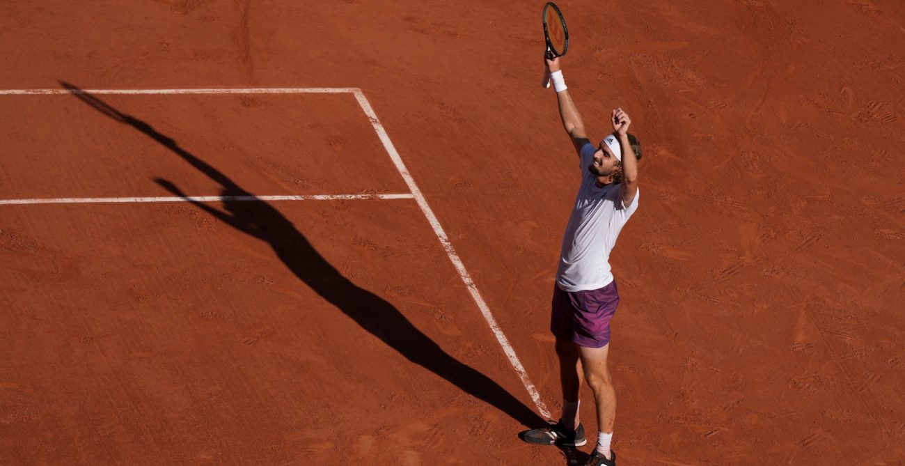Stefanos Tsitsipas celebrates a win with his arms up in the air
