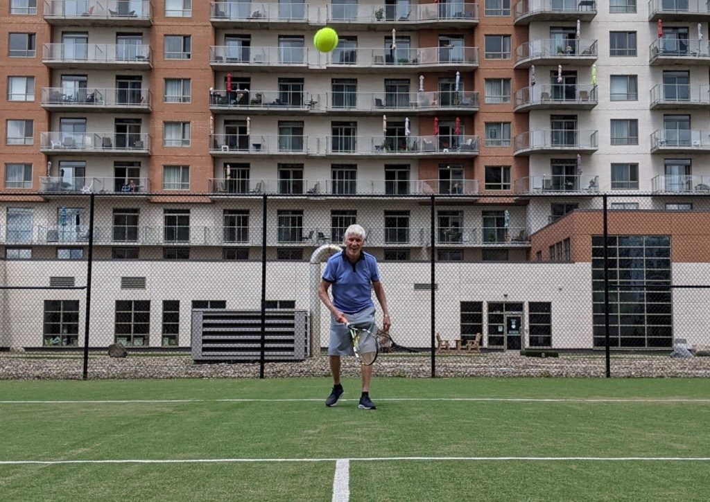 A senior tennis player on court smiling