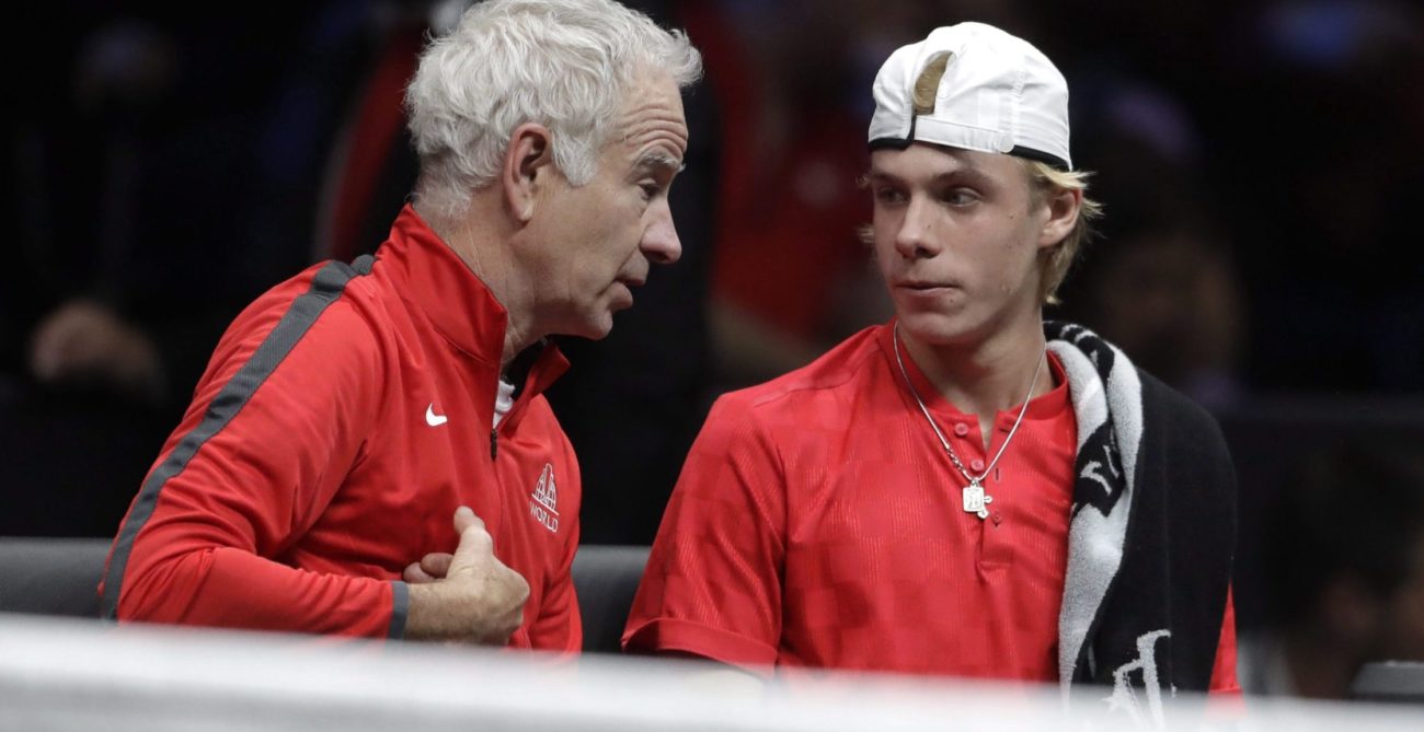 John McEnroe (left) leans in and talks to Denis Shapovalov