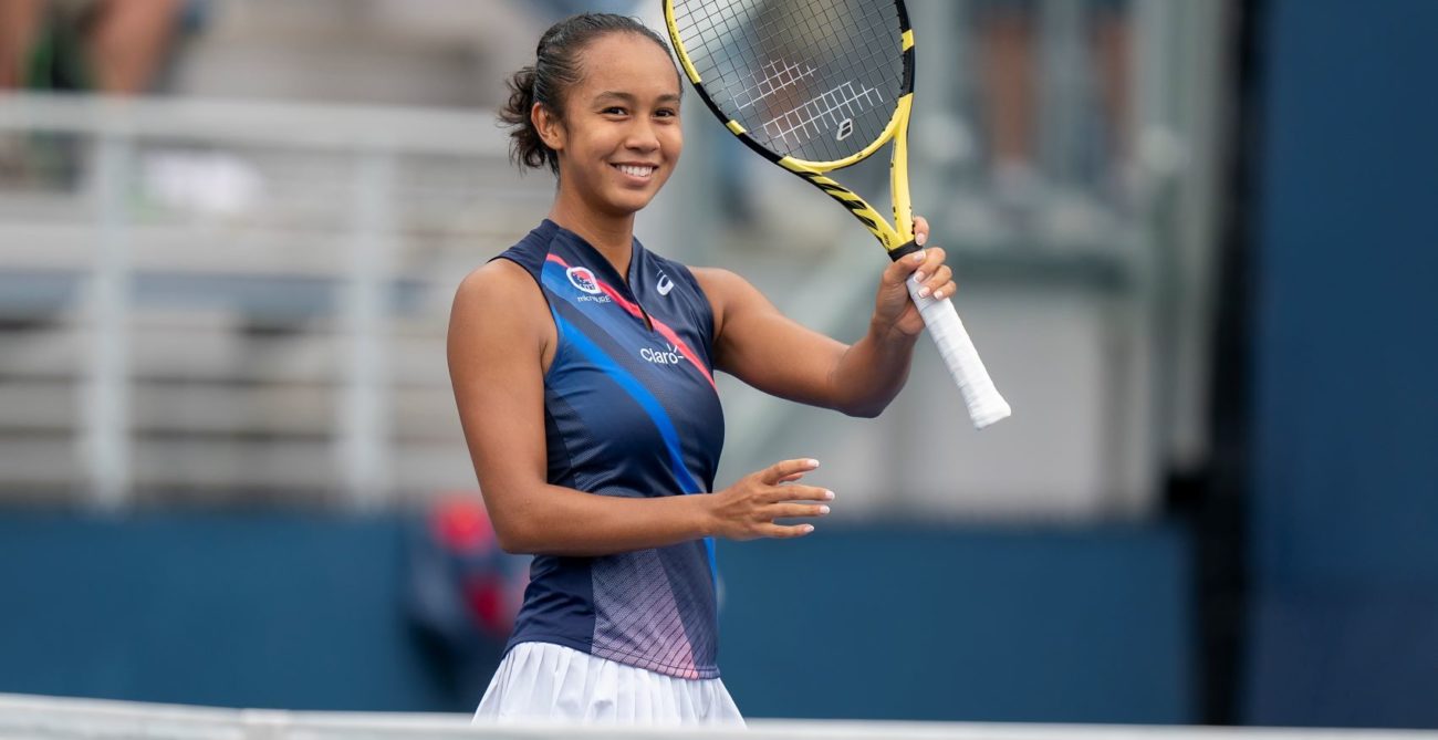 Leylah Fernandez smiles and raises her racket.