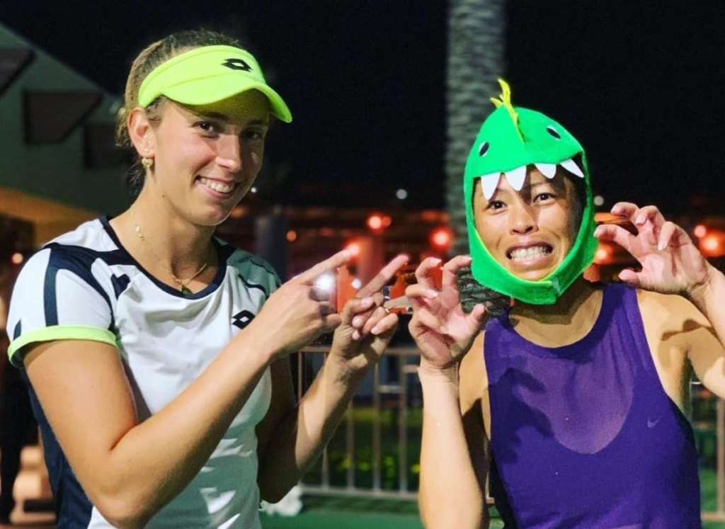 Elise Mertens (left) points at Su-Wei Hsieh who is wearing a dragon cap and growling.