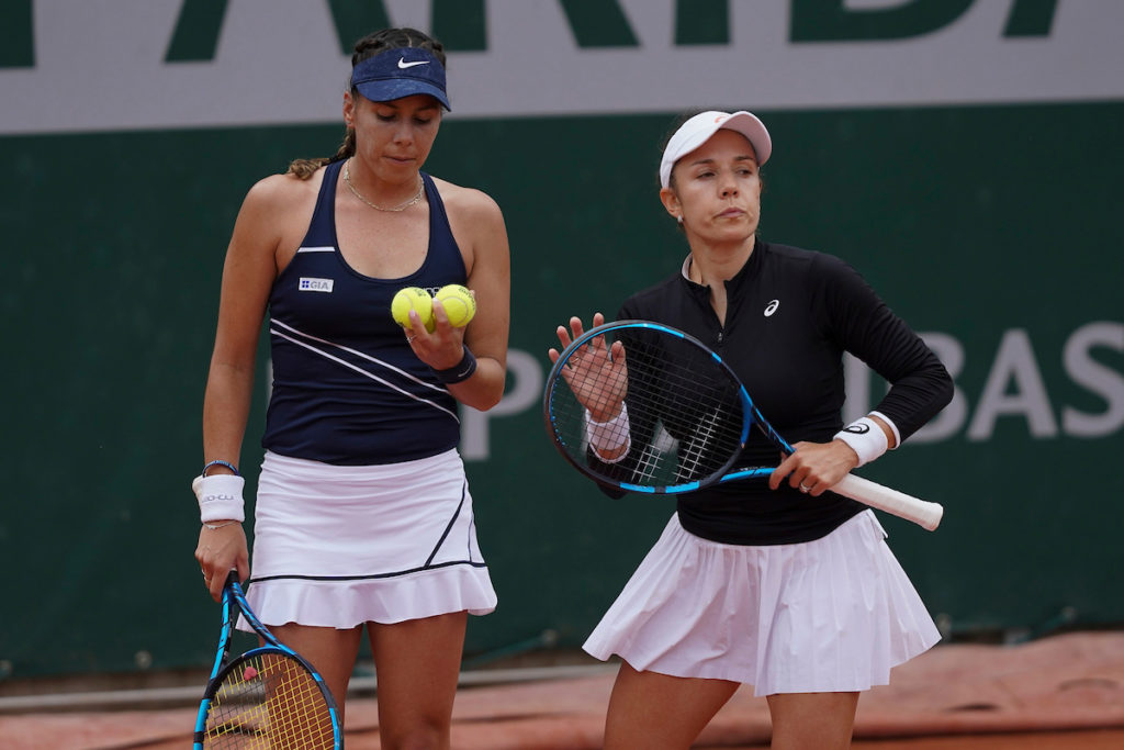 Giuliana Olmos looks at the balls while standing next to Sharon Fichman.