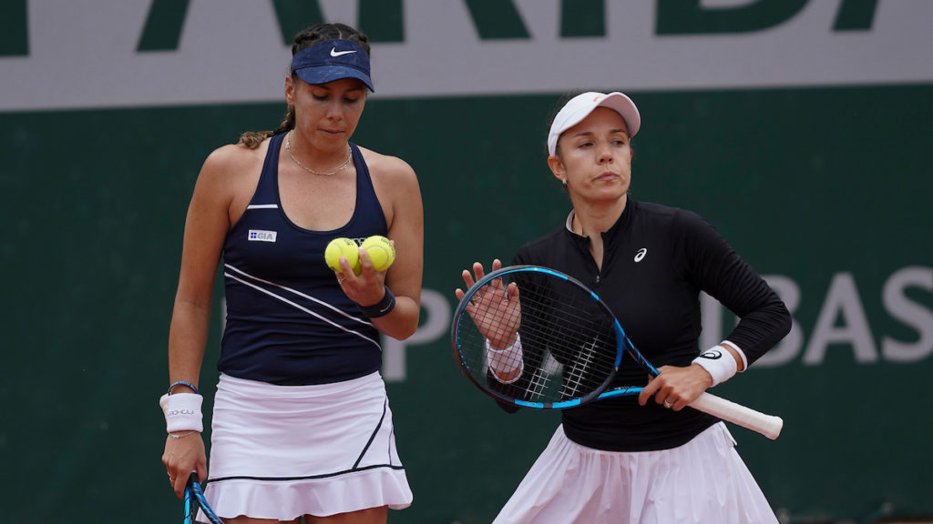 Giuliana Olmos looks at the balls while standing next to Sharon Fichman.