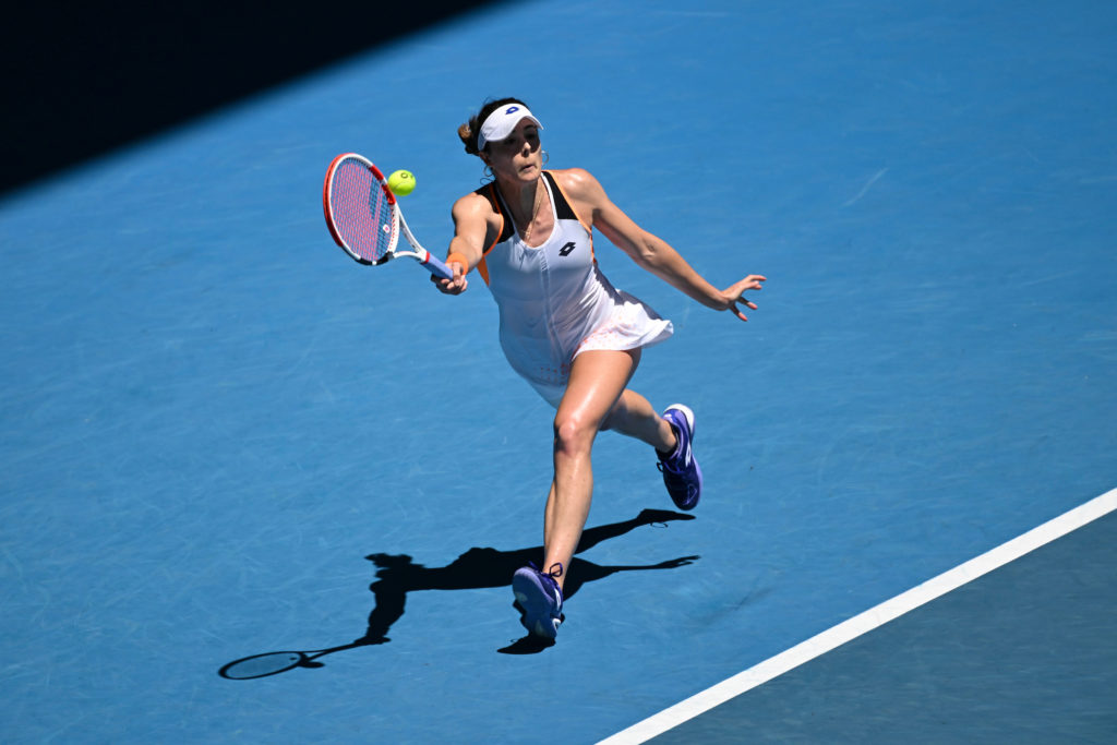 Alize Cornet lunges and hits a forehand.