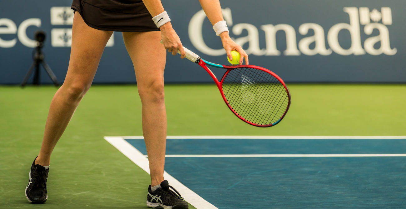 tennis player ready to serve, viewed from waist down
