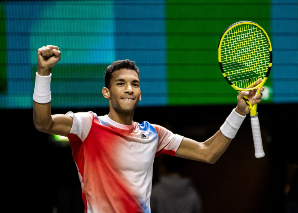 Felix Auger-Aliassime raises his arms in celebration.