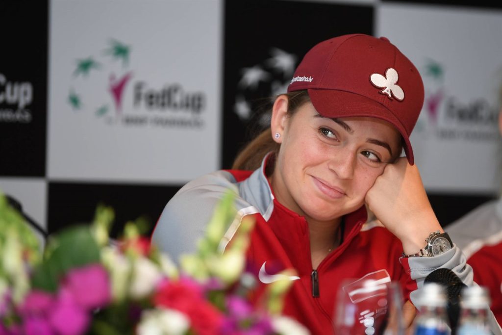 Jelena Ostapenko leans on her hand and smiles.