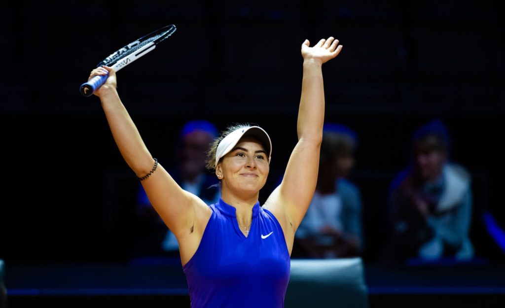 Bianca Andreescu raises her arms over head head in celebration.