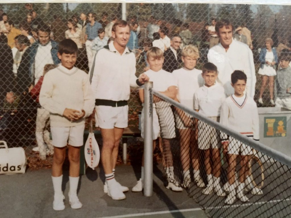 Rod Laver and John Newcombe posing for a picture with kids at a tennis court in British Columbia