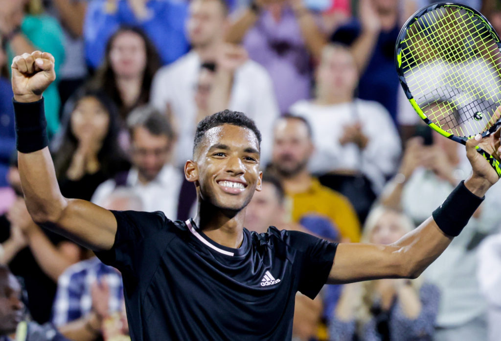 Felix Auger-Aliassime raises his hands in victory.
