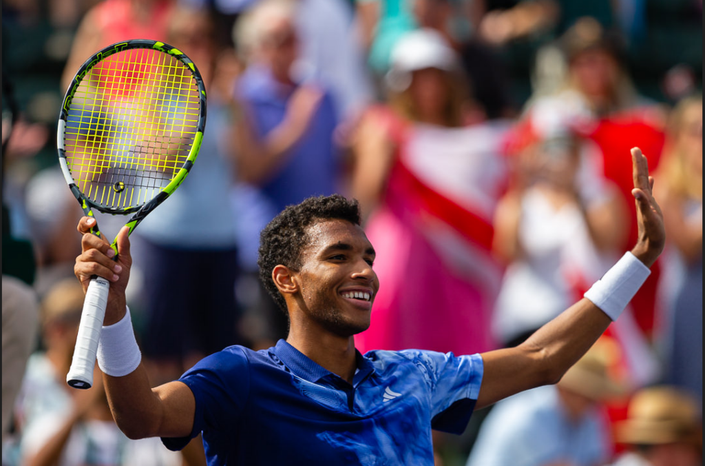 Felix Auger-Aliassime raises his arms in celebration.