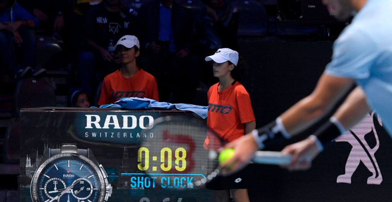 A player prepares to serve with the shot clock visible in the background.
