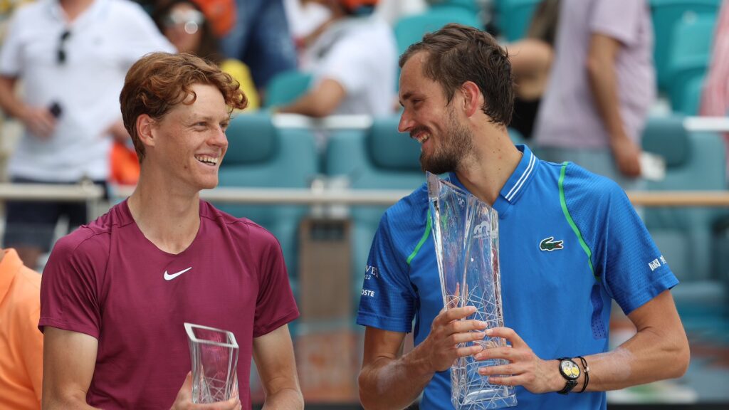 Jannik Sinner (left) and Daniil Medvedev look at each other and smile while holding their Miami trophies.
