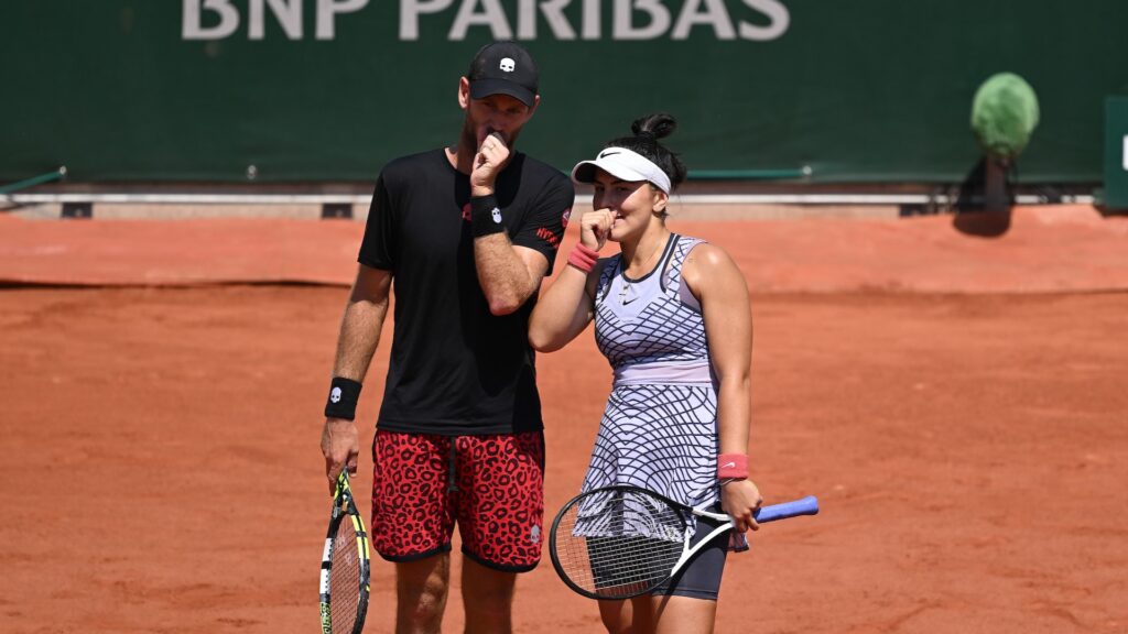 Bianca Andreescu (right) and Michael Venus lean close and cover their mouths as they strategize.