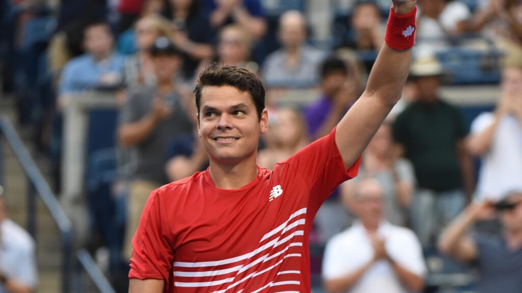 Milos Raonic raises a thumbs up above his head.