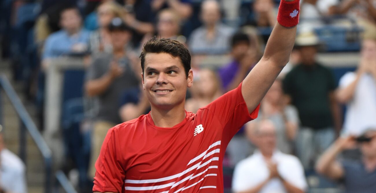 Milos Raonic raises a thumbs up above his head.