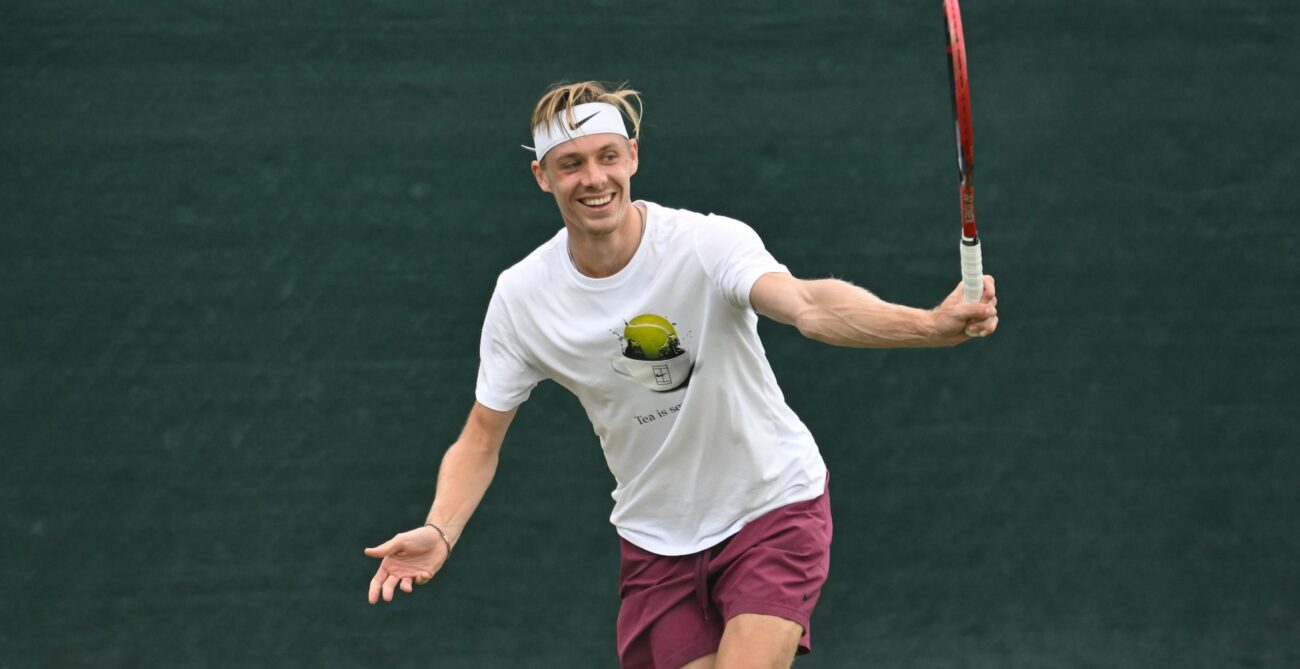 Denis Shapovalov hits a backhand and smiles.