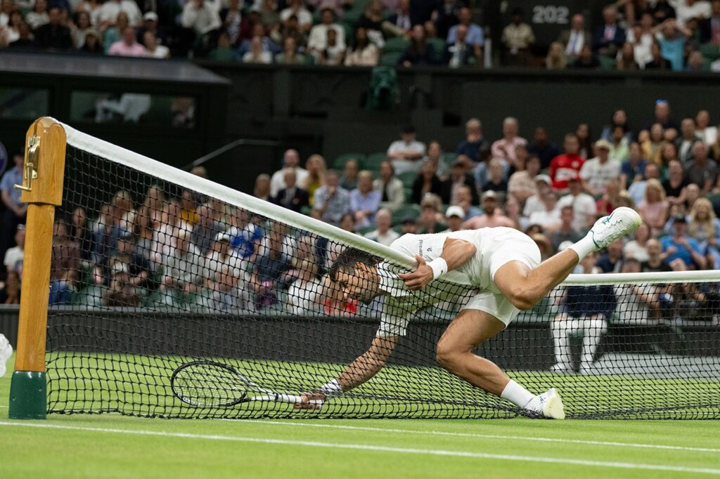 Novak Djokovic falls over the net at Wimbledon.