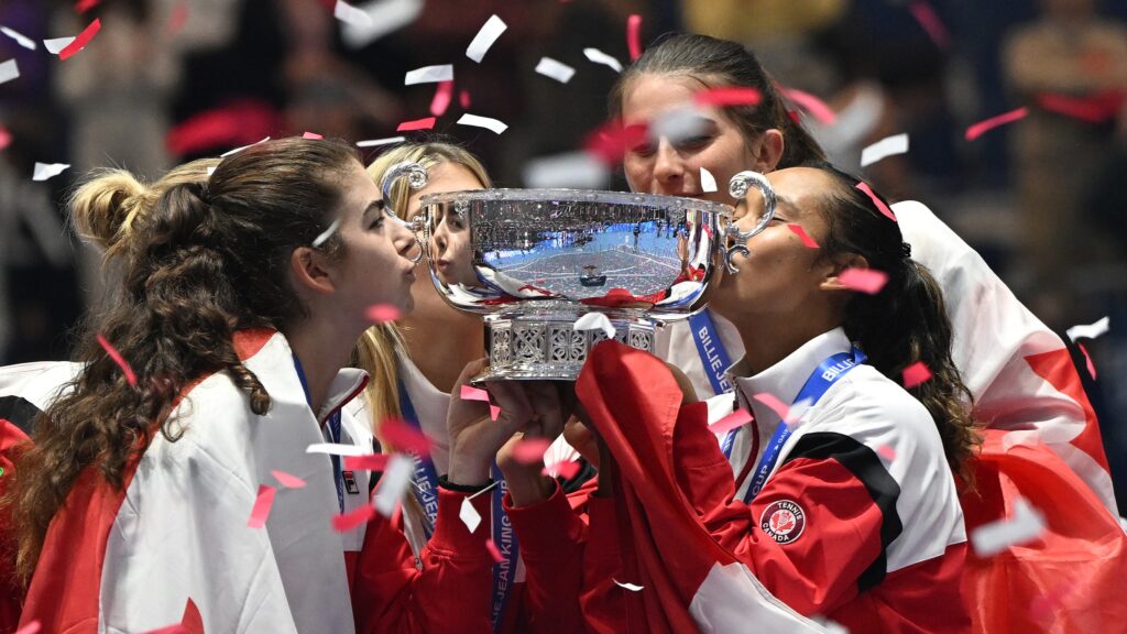 Marina Stakusic (left) and Leylah Fernandez (right) kiss the Billie Jean King Cup trophy.