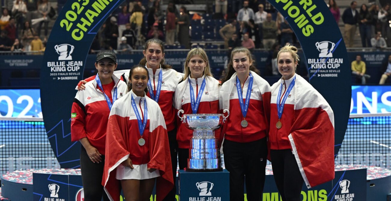 From left to right, Heidi El Tabakh, Leylah Fernandez, Rebecca Marino, Eugenie Bouchard, Marina Stakusic, and Gabriela Dabrowski wear their medals and stand behind the Billie Jean King Cup trophy, the World Cup of Tennis.