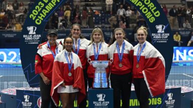 From left to right, Heidi El Tabakh, Leylah Fernandez, Rebecca Marino, Eugenie Bouchard, Marina Stakusic, and Gabriela Dabrowski wear their medals and stand behind the Billie Jean King Cup trophy, the World Cup of Tennis.