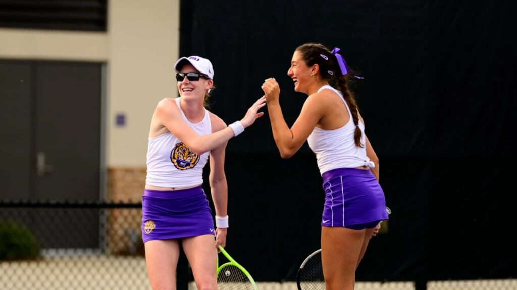 Kayla Cross (left) and Cadence Brace (right) high five and laugh during their doubles match for LSU in the NCAA. They are the top Canadian pair in the American university tennis system.