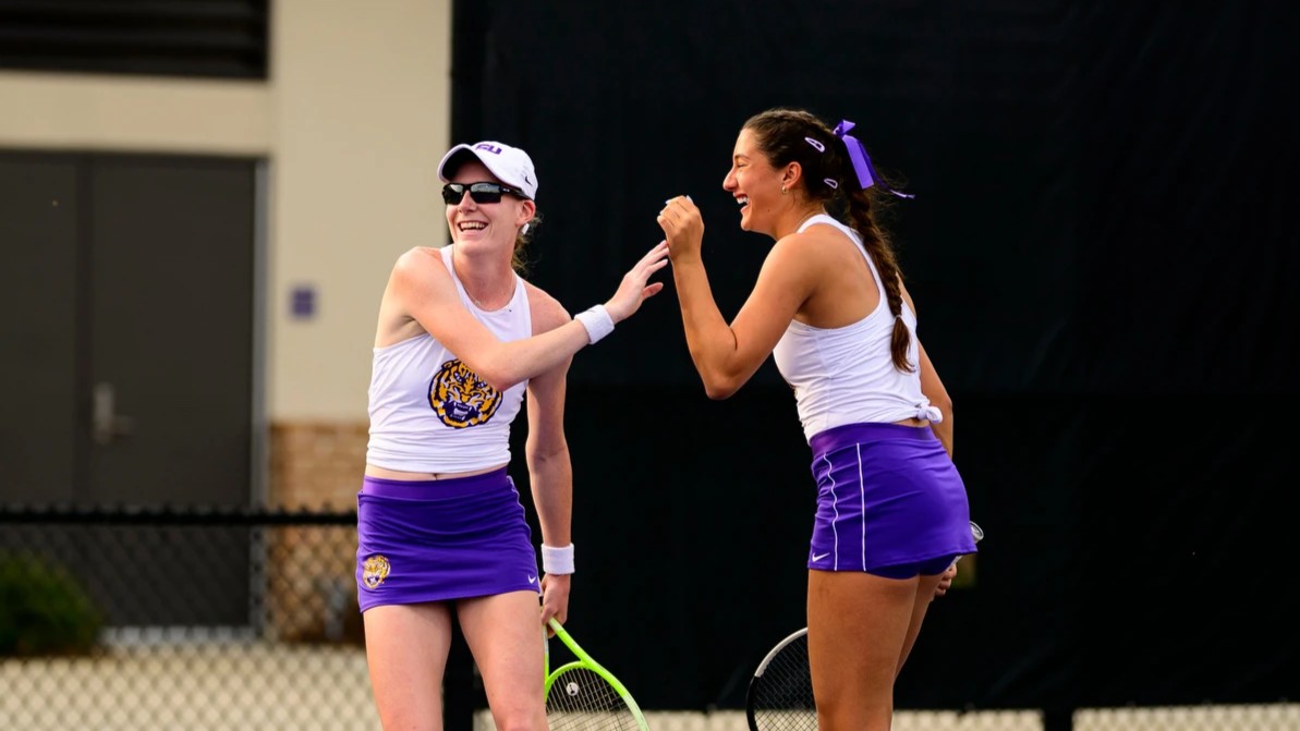 Kayla Cross (left) and Cadence Brace (right) high five and laugh during their doubles match for LSU in the NCAA. They are the top Canadian pair in the American university tennis system.